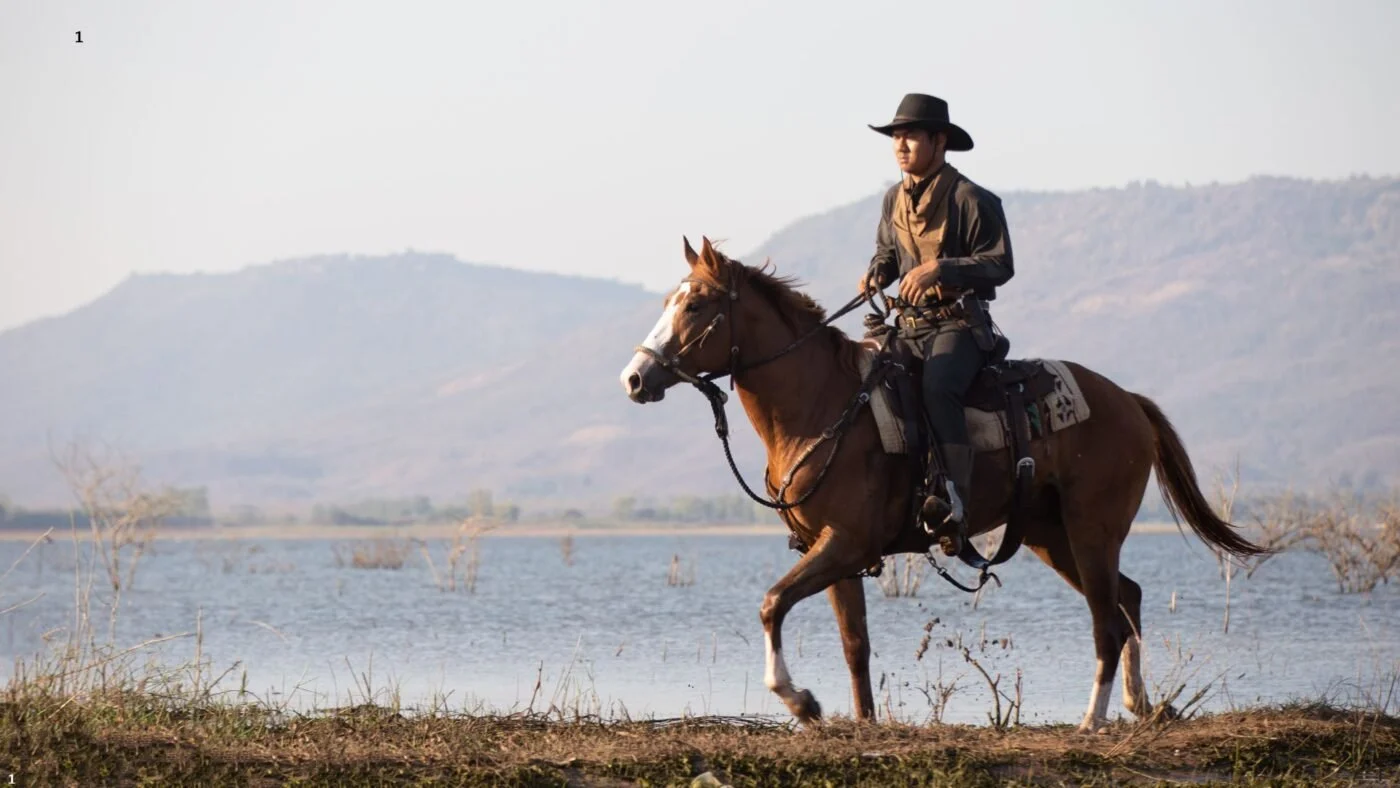 Cowboy riding his horse with heavy western saddle and gear.
