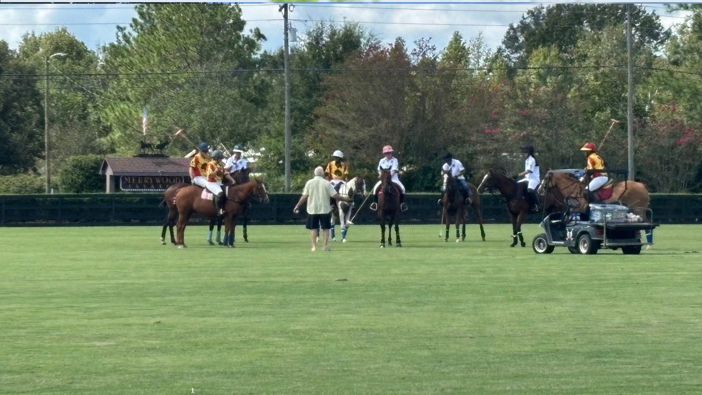 Polo players on horseback gathered at center field before an outdoor match
