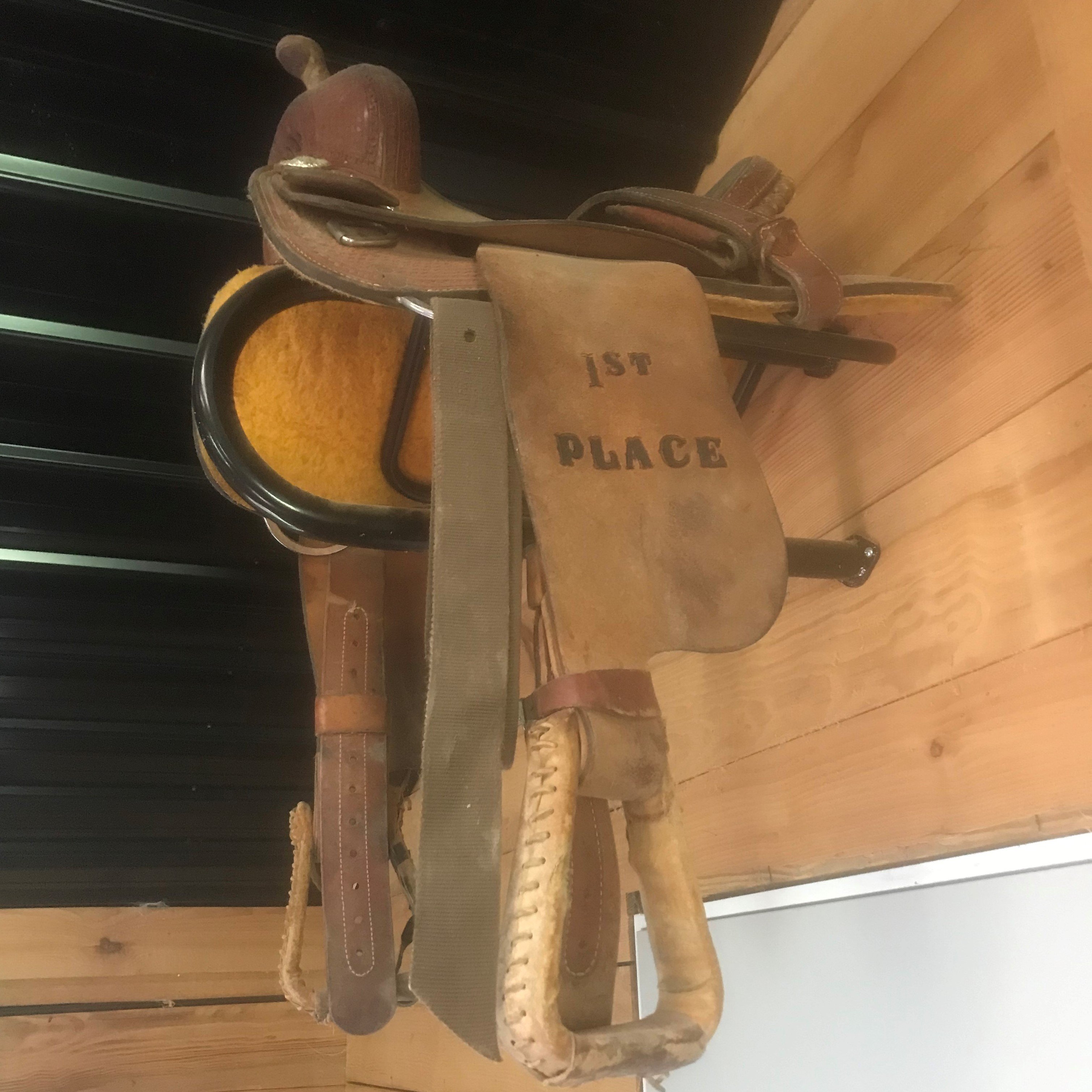 Picture of a western saddle stored on a saddle rack.