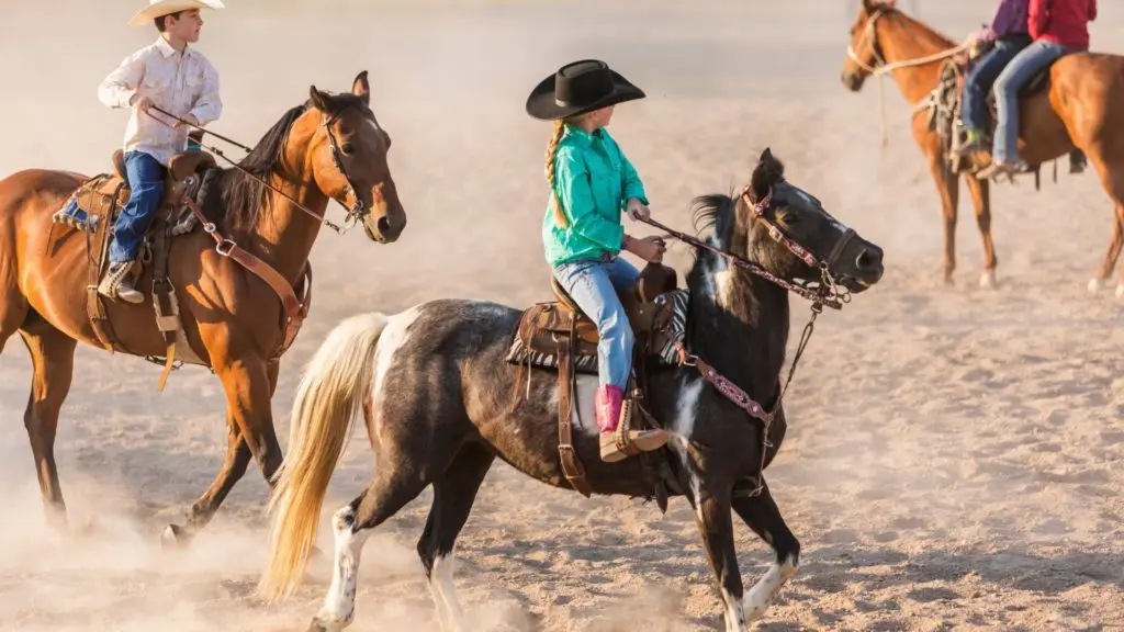 Children riding Western-style horses, illustrating the snug fit of riding boots for safety