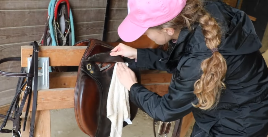 Picture a woman cleaning an English saddle.