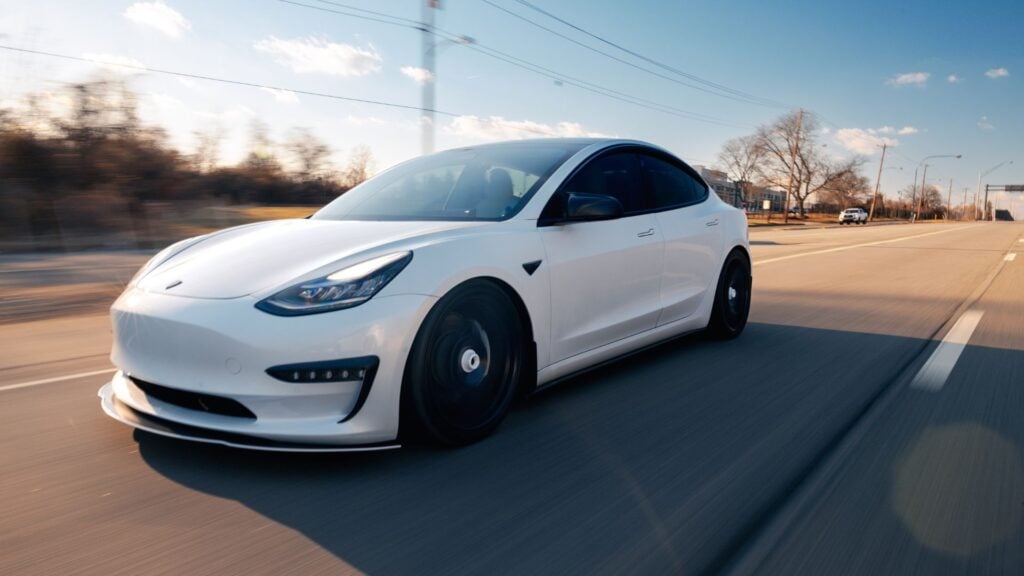 Picture of a tesla driving on a highway.