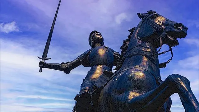 Bronze statue of Joan of Arc riding a dapple gray warhorse, symbolizing medieval nobility.