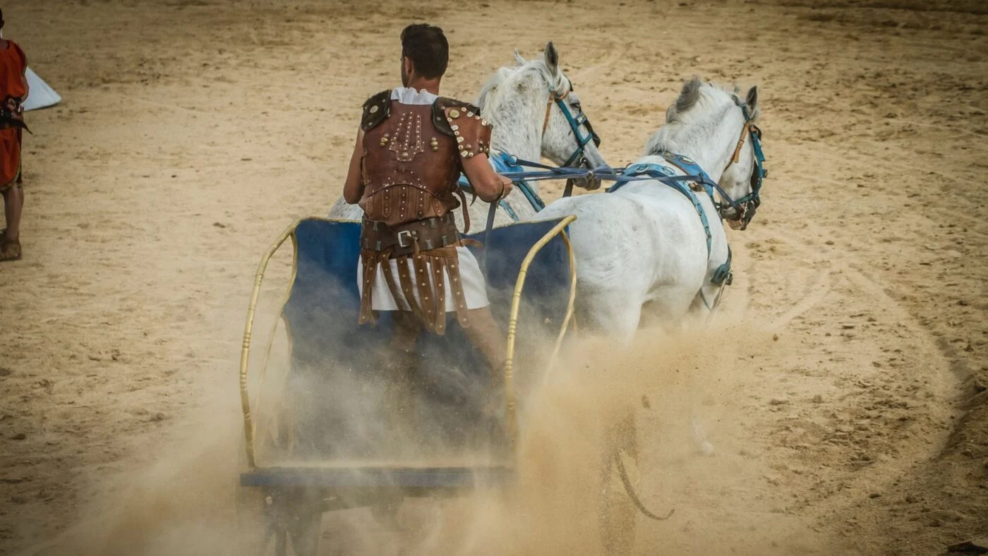 Gray warhorse charging with a soldier in historical battle gear.