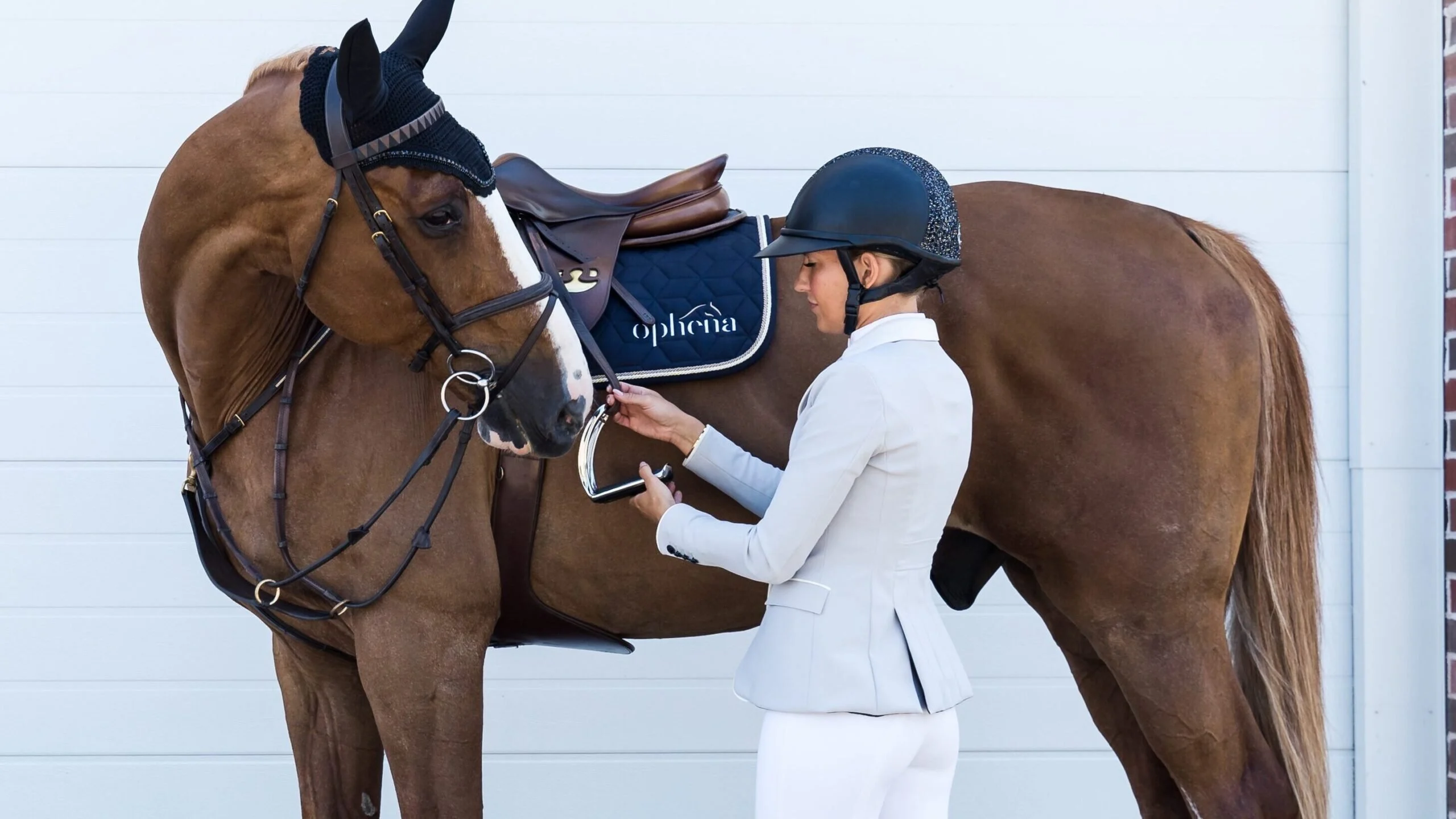 Essential Horse Riding Gear: Beyond the Helmet Equestrian adjusting a saddle, highlighting the importance of essential horse riding gear.