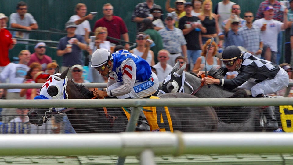 Thoroughbred horses rounding the turn on the dirt track during the Breeders' Cup World Championships at Santa Anita Park.