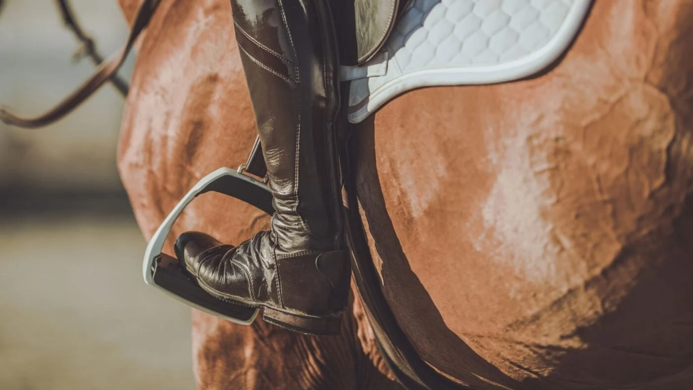 Close-up of a riding boot heel resting correctly on an English stirrup for safety