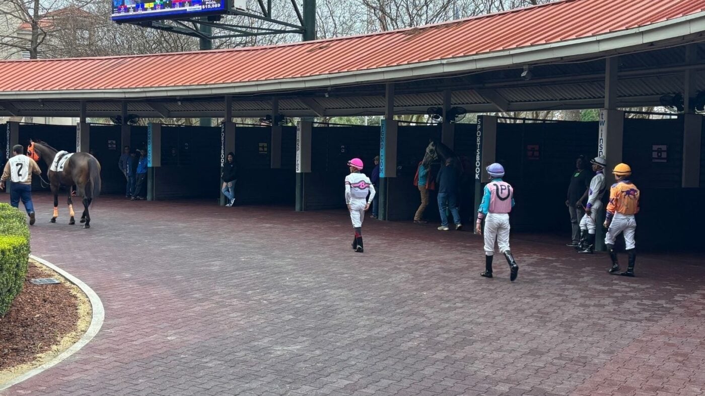 Jockeys in the paddock walking towards their mounts. Each will have different weights added. 